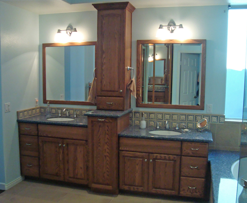 This is an example of a mid-sized traditional master bathroom in Orange County with an undermount sink, raised-panel cabinets, medium wood cabinets, engineered quartz benchtops, an undermount tub, a corner shower, a two-piece toilet, beige tile, porcelain tile, blue walls and porcelain floors.