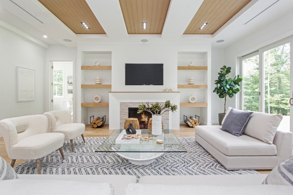 Inspiration for a large contemporary open concept light wood floor and coffered ceiling family room remodel in New York with white walls, a standard fireplace, a stacked stone fireplace and a wall-mounted tv