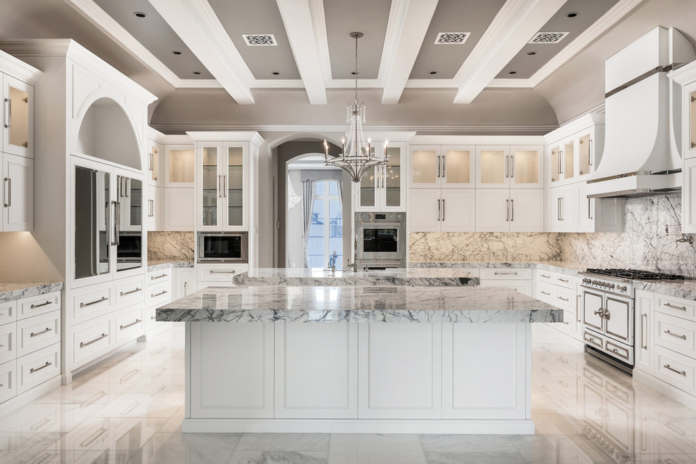 Photo of an expansive mediterranean u-shaped separate kitchen in Phoenix with marble floors, white floor, a drop-in sink, glass-front cabinets, white cabinets, marble benchtops, multi-coloured splashback, marble splashback, stainless steel appliances and multiple islands.