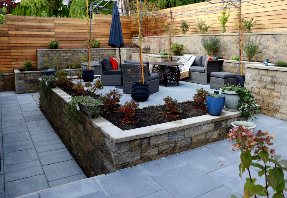 Design ideas for a mid-sized contemporary backyard concrete paver and wood fence retaining wall landscape in Vancouver.