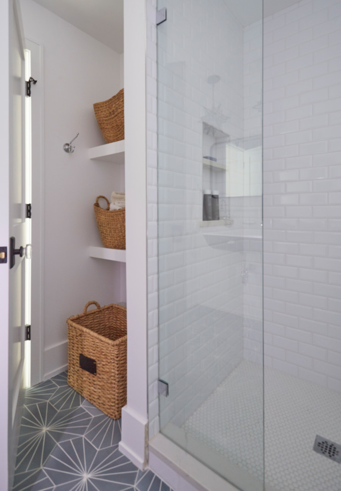 This is an example of a mid-sized country bathroom in Chicago with an alcove shower, a two-piece toilet, white tile, ceramic tile, white walls, cement tiles, a wall-mount sink, turquoise floor, a hinged shower door, a niche and a single vanity.