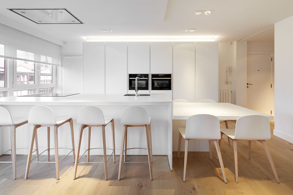 This is an example of a large contemporary single-wall open plan kitchen in Other with a single-bowl sink, flat-panel cabinets, white cabinets, medium hardwood floors and with island.