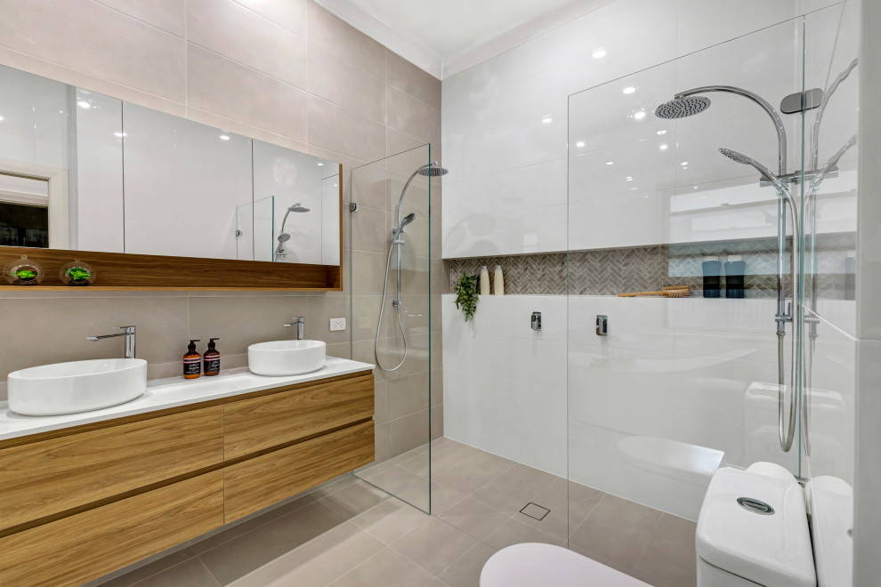This is an example of a contemporary master bathroom in Adelaide with flat-panel cabinets, medium wood cabinets, a curbless shower, beige tile, multi-coloured tile, a vessel sink, engineered quartz benchtops, beige floor, an open shower, white benchtops, a double vanity and a floating vanity.