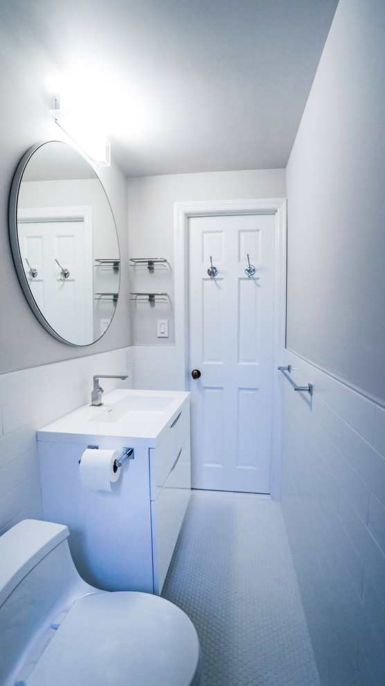 Inspiration for a mid-sized contemporary bathroom in New York with white cabinets, a one-piece toilet, white tile, ceramic tile, white walls, ceramic floors, a drop-in sink, engineered quartz benchtops, white floor and a hinged shower door.