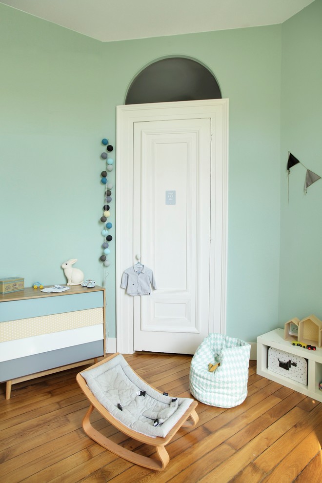 This is an example of a mid-sized scandinavian nursery for boys in Dijon with green walls and medium hardwood floors.