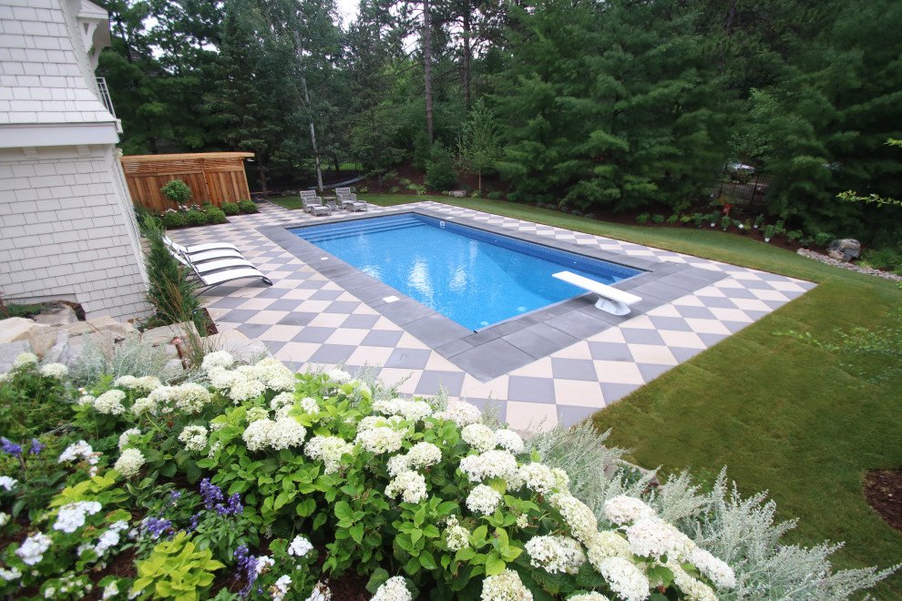 This is an example of a medium sized vintage back rectangular lengths swimming pool in Minneapolis with with pool landscaping and concrete paving.