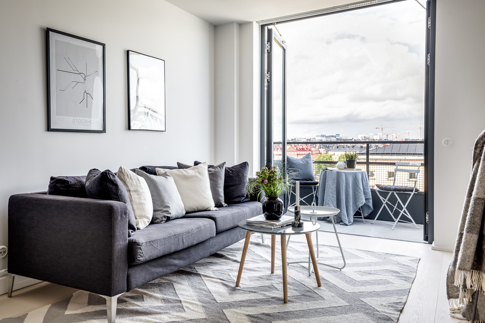Scandinavian living room in Stockholm with white walls, light hardwood floors and beige floor.