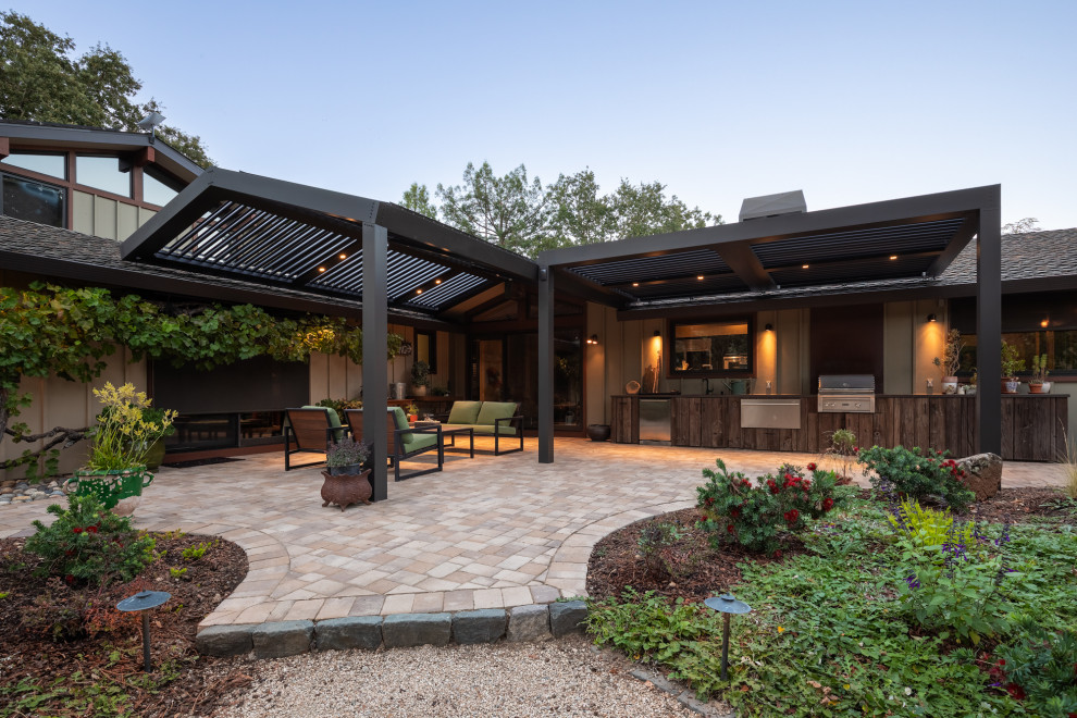 Photo of a large modern backyard patio in Los Angeles with natural stone pavers and a roof extension.