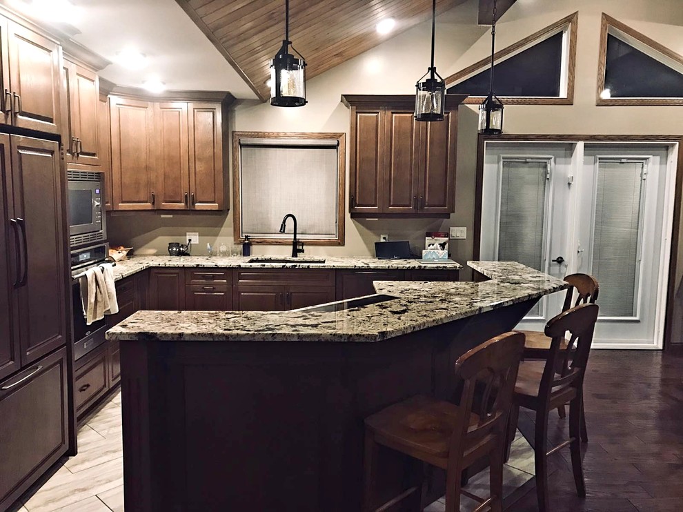 Eat-in kitchen - mid-sized rustic l-shaped ceramic tile and multicolored floor eat-in kitchen idea with an undermount sink, shaker cabinets, brown cabinets, granite countertops, stainless steel appliances and an island