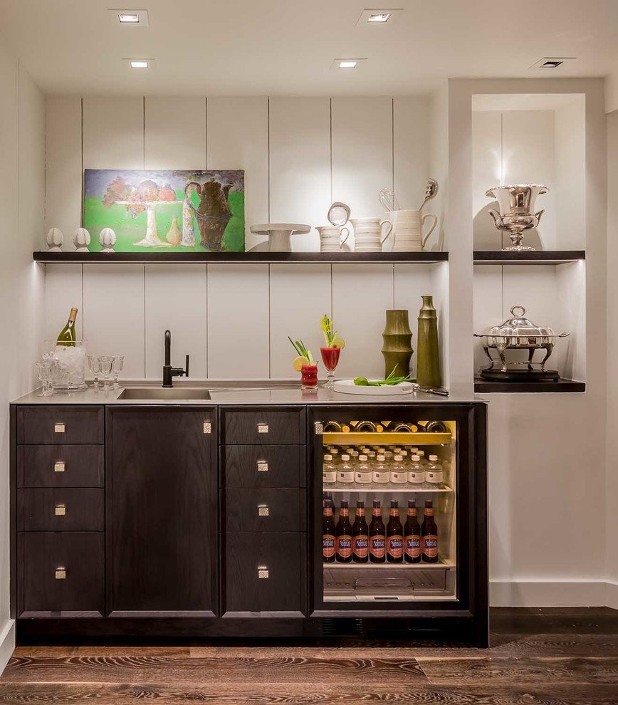 Photo of a small contemporary single-wall wet bar in Chicago with an integrated sink, flat-panel cabinets, black cabinets, stainless steel benchtops, white splashback, timber splashback and dark hardwood floors.