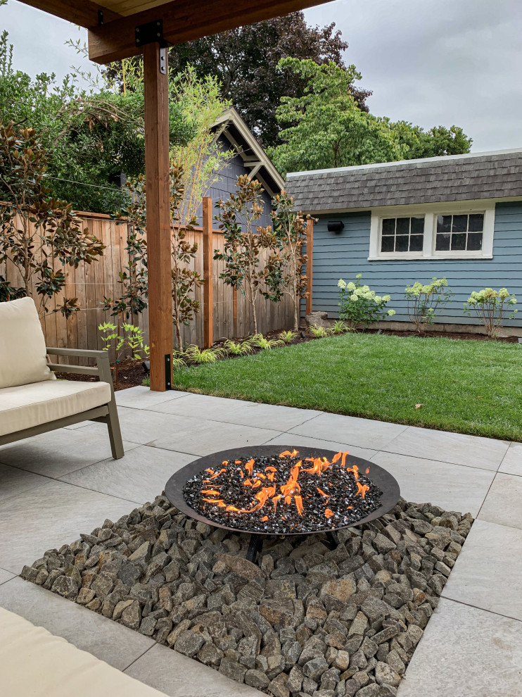This is an example of a small modern backyard partial sun garden for summer in Portland with natural stone pavers and a wood fence.