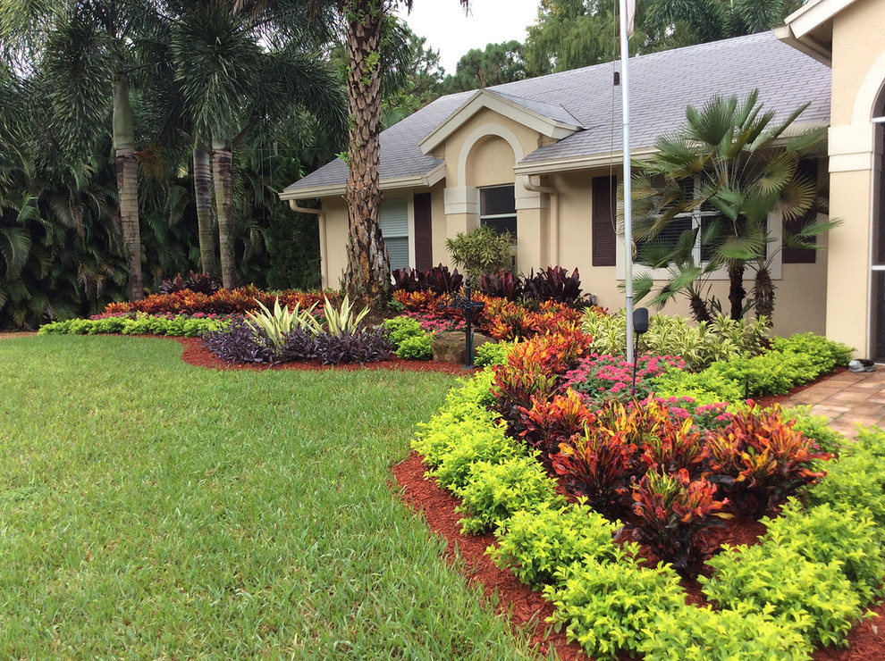 This is an example of a mid-sized tropical front yard full sun garden in Miami with concrete pavers and a garden path.