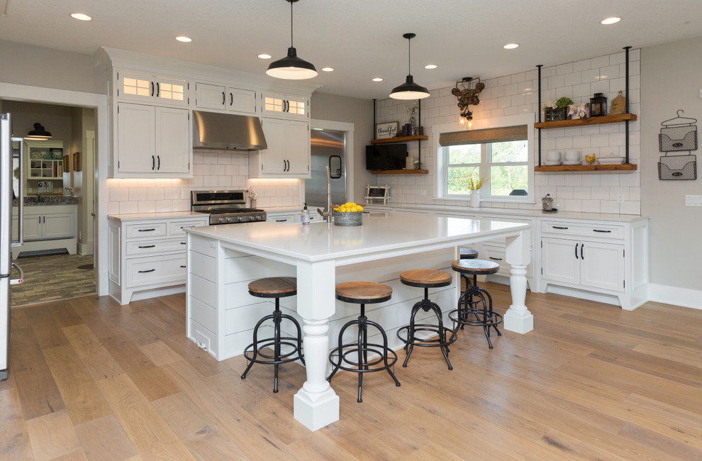 Inspiration for a country kitchen in Other with shaker cabinets, white cabinets, white splashback, stainless steel appliances, light hardwood floors, with island and beige floor.
