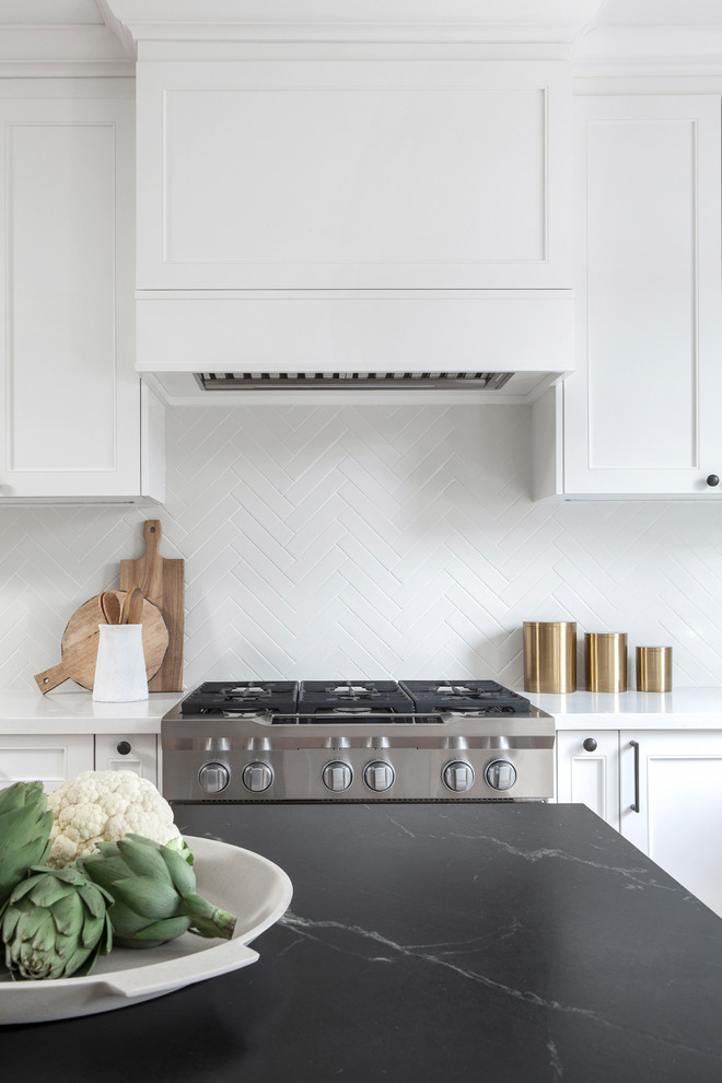 Small transitional l-shaped light wood floor and brown floor kitchen pantry photo in Toronto with a double-bowl sink, recessed-panel cabinets, white cabinets, soapstone countertops, white backsplash, porcelain backsplash, stainless steel appliances, an island and black countertops