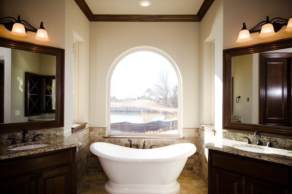 Inspiration for a large transitional master bathroom in Oklahoma City with raised-panel cabinets, dark wood cabinets, a freestanding tub, ceramic tile, beige walls, ceramic floors, an undermount sink, beige tile, engineered quartz benchtops and beige floor.
