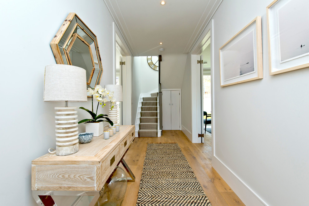 Mid-sized transitional hallway in London with light hardwood floors, brown floor and white walls.