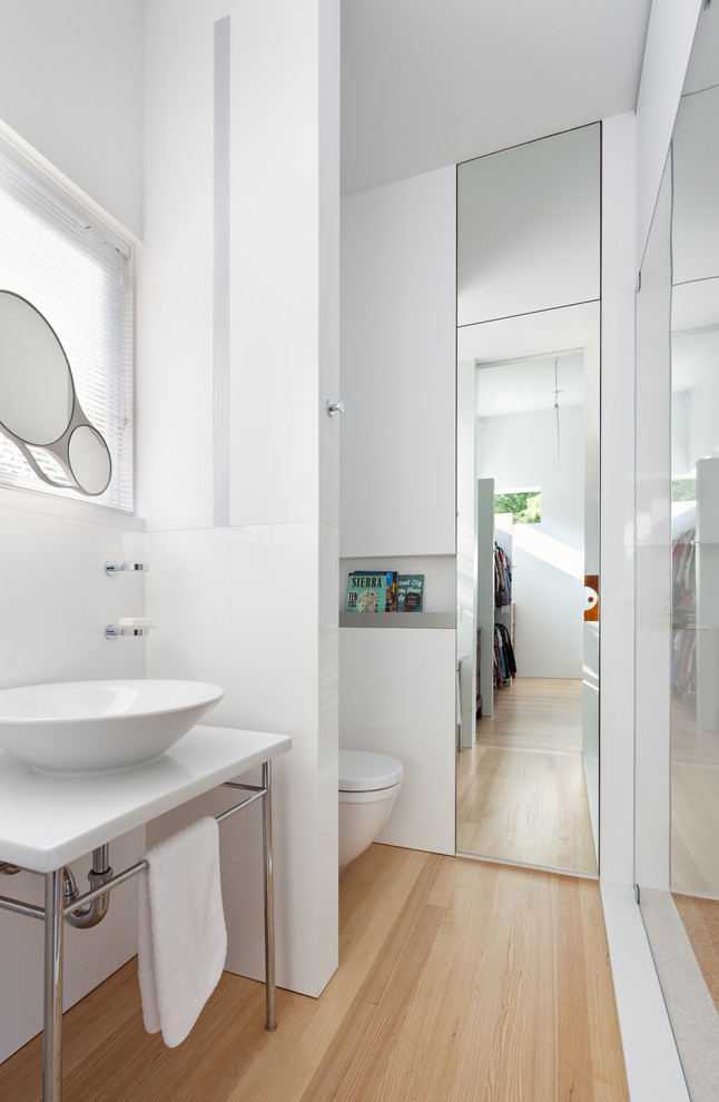 Inspiration for a small contemporary master bathroom in DC Metro with a vessel sink, engineered quartz benchtops, an alcove shower, a wall-mount toilet, white tile, porcelain tile, white walls and light hardwood floors.