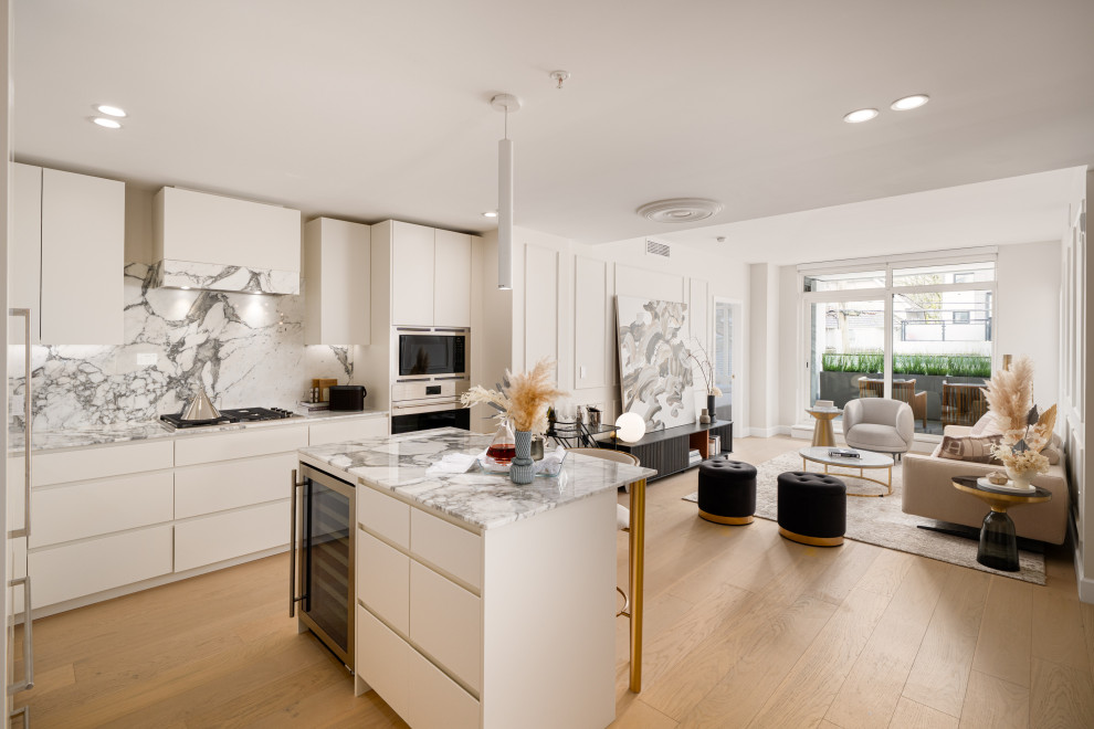Example of a trendy l-shaped medium tone wood floor and brown floor kitchen design with flat-panel cabinets, white cabinets, gray backsplash, stone slab backsplash, stainless steel appliances, an island and gray countertops