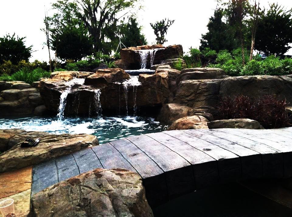 Country backyard custom-shaped lap pool in Ottawa with a water feature and natural stone pavers.