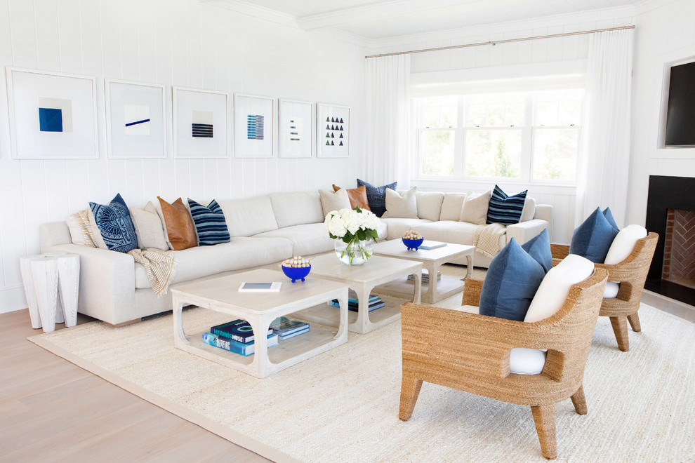 Photo of a large beach style formal open concept living room in New York with white walls, light hardwood floors, a standard fireplace, beige floor, a plaster fireplace surround and no tv.