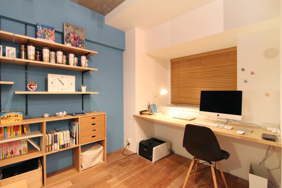 Scandinavian home office in Tokyo with blue walls, medium hardwood floors and brown floor.