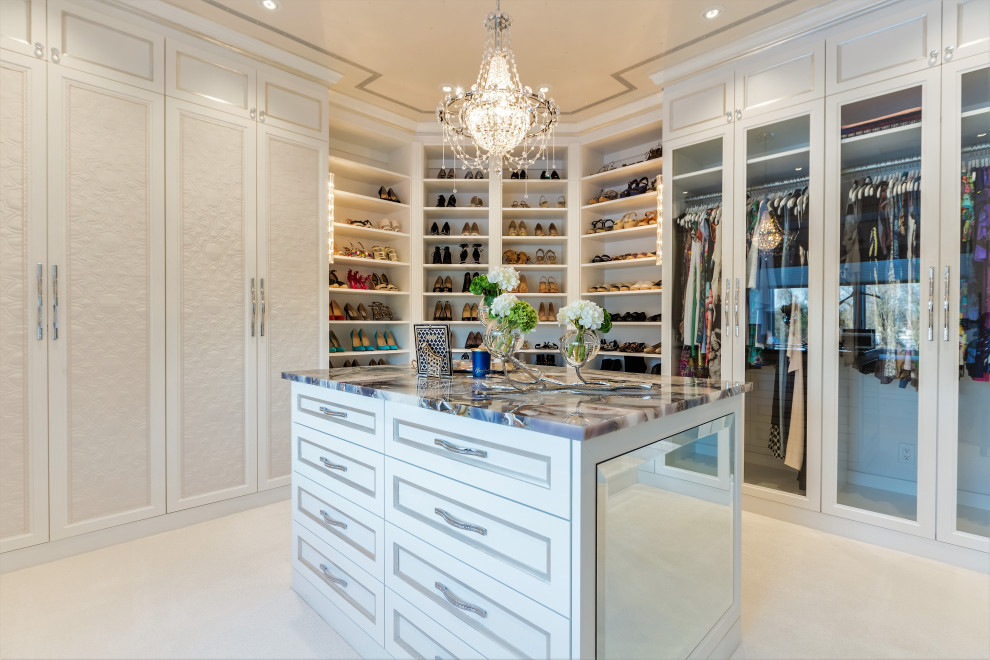 Inspiration for a large traditional women's walk-in wardrobe in New York with glass-front cabinets, beige cabinets, carpet and white floor.
