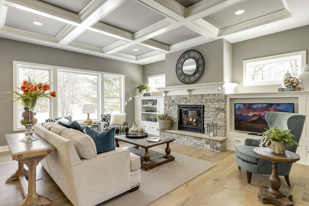 Photo of a large transitional open concept living room in Minneapolis with grey walls, light hardwood floors, a standard fireplace, a stone fireplace surround, a built-in media wall and beige floor.