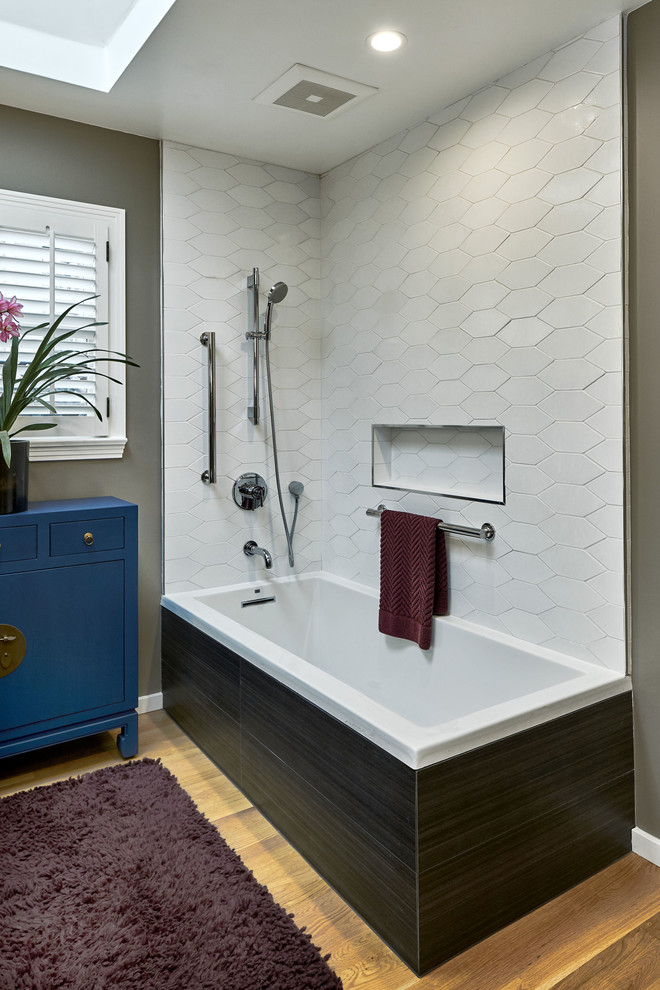 Design ideas for a small transitional 3/4 bathroom in San Francisco with flat-panel cabinets, blue cabinets, a corner tub, a shower/bathtub combo, a one-piece toilet, white tile, ceramic tile, grey walls, light hardwood floors, a pedestal sink, yellow floor, an open shower and white benchtops.