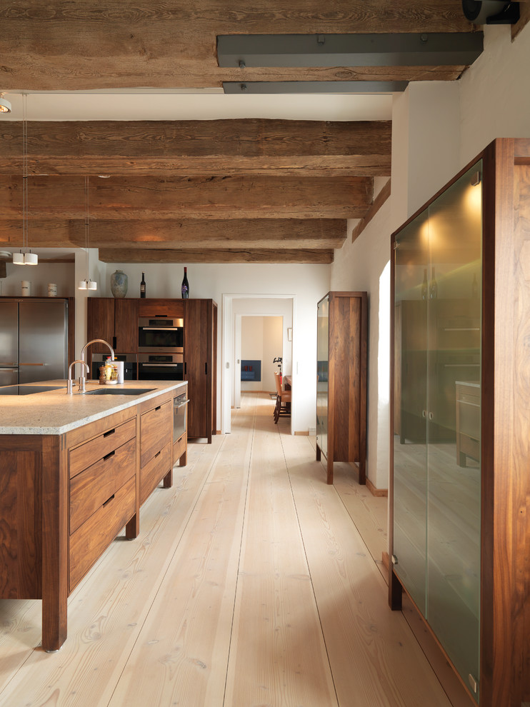 Inspiration for a country galley open plan kitchen in Copenhagen with an undermount sink, flat-panel cabinets, medium wood cabinets, stainless steel appliances, light hardwood floors and with island.
