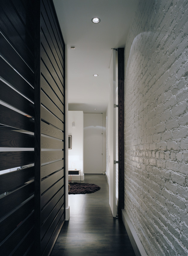 This is an example of a mid-sized industrial hallway in New York with white walls and dark hardwood floors.