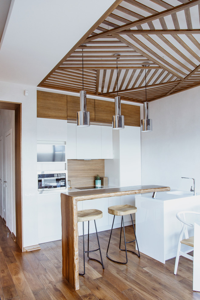 Contemporary galley eat-in kitchen in Saint Petersburg with flat-panel cabinets, white cabinets, brown splashback, medium hardwood floors, a peninsula and brown floor.