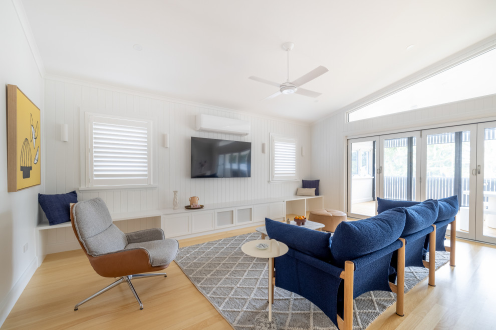This is an example of a mid-sized beach style open concept family room in Townsville with a library, white walls, light hardwood floors and wood walls.