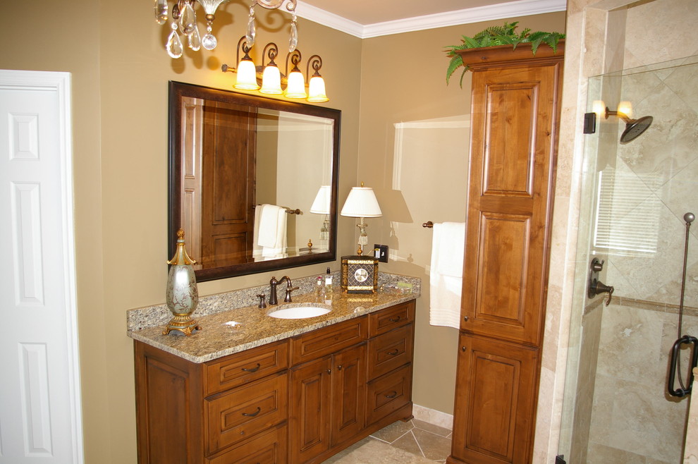 Large transitional master beige tile and porcelain tile porcelain tile and beige floor drop-in bathtub photo in Atlanta with an undermount sink, raised-panel cabinets, medium tone wood cabinets, granite countertops, a two-piece toilet, beige walls and a hinged shower door