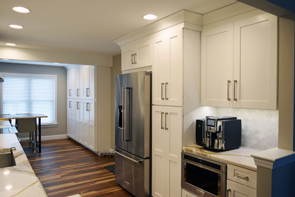 Transitional medium tone wood floor kitchen photo with an undermount sink, shaker cabinets, white cabinets, quartz countertops, white backsplash, marble backsplash, stainless steel appliances, no island and white countertops