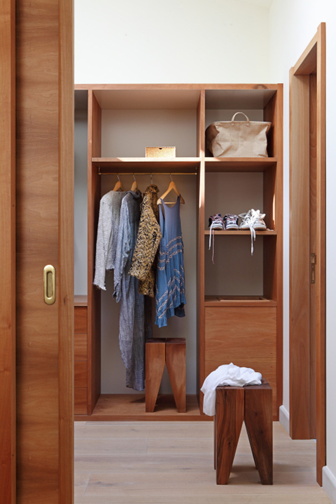 Photo of a mid-sized transitional gender-neutral walk-in wardrobe in Valencia with open cabinets, medium wood cabinets and light hardwood floors.