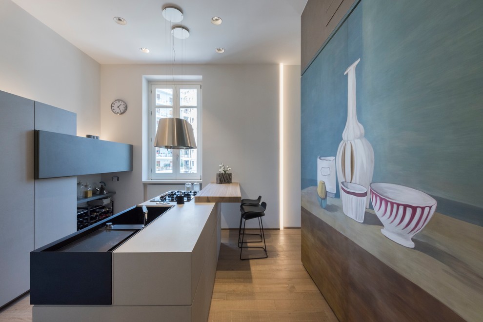 This is an example of a contemporary kitchen in Catania-Palermo with a single-bowl sink, wood benchtops, panelled appliances, light hardwood floors and with island.