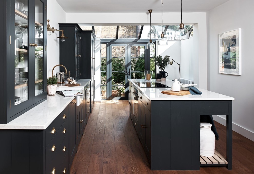 Mid-sized transitional galley separate kitchen in Kent with a farmhouse sink, granite benchtops, white splashback, panelled appliances, dark hardwood floors, with island, brown floor, shaker cabinets and grey cabinets.