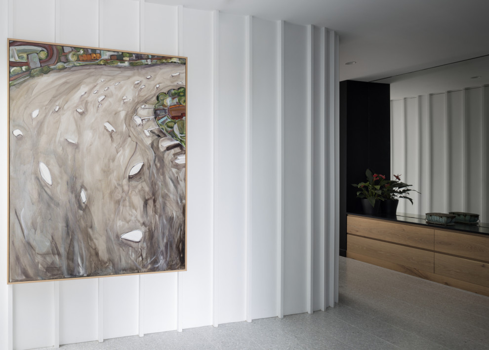 Photo of a mid-sized contemporary foyer in Brisbane with white walls, terrazzo floors, a pivot front door, a glass front door, grey floor, recessed and decorative wall panelling.