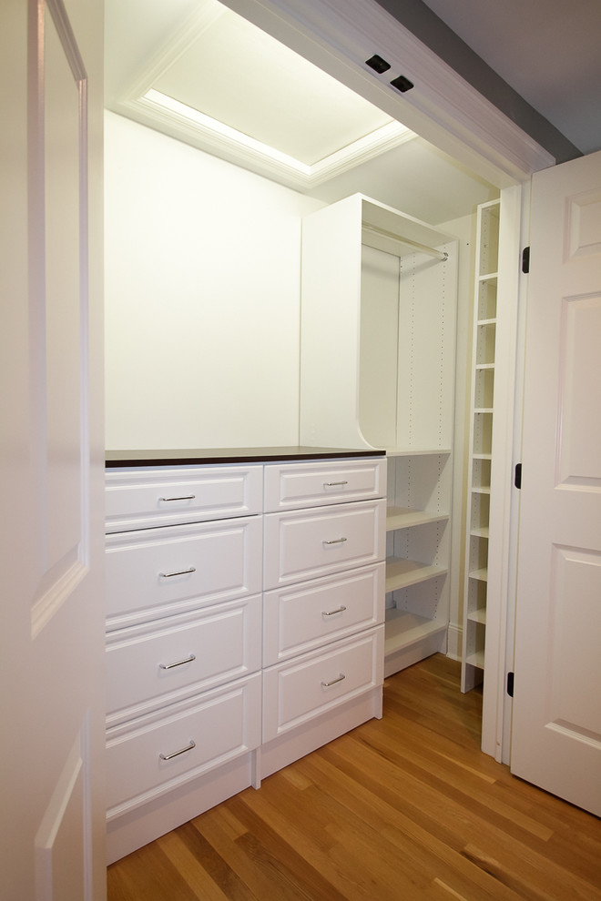 Design ideas for a mid-sized traditional gender-neutral built-in wardrobe in New York with raised-panel cabinets, white cabinets and medium hardwood floors.