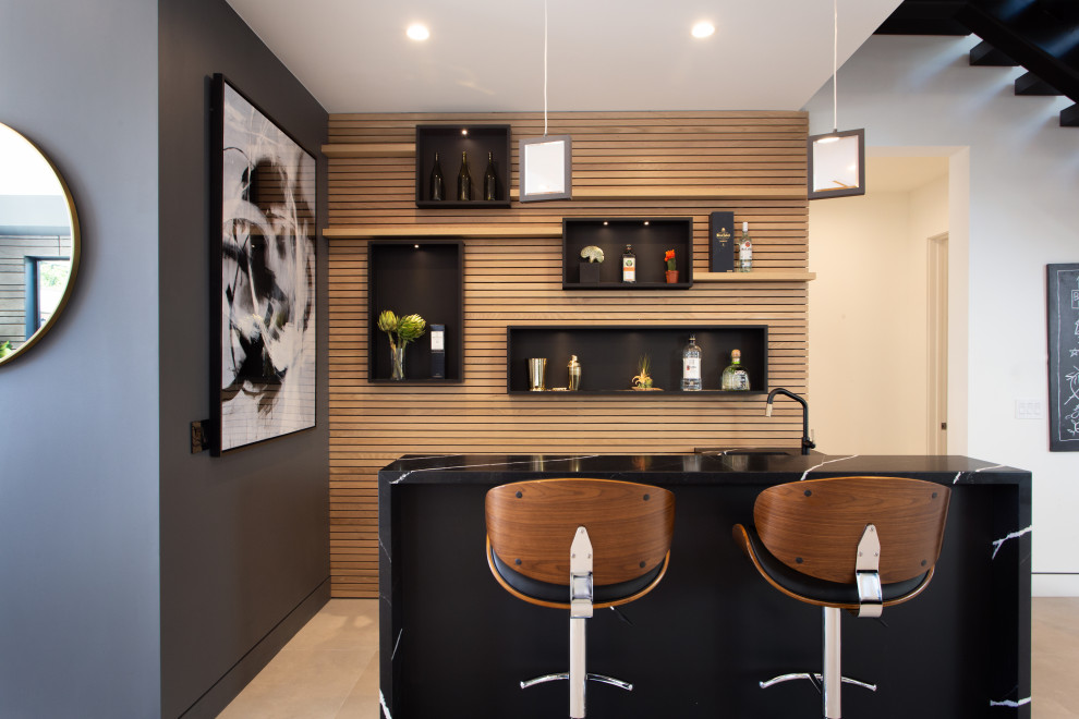 Photo of a small modern single-wall wet bar in Los Angeles with an undermount sink, open cabinets, black cabinets, soapstone benchtops, brown splashback, timber splashback, black benchtop, concrete floors and grey floor.