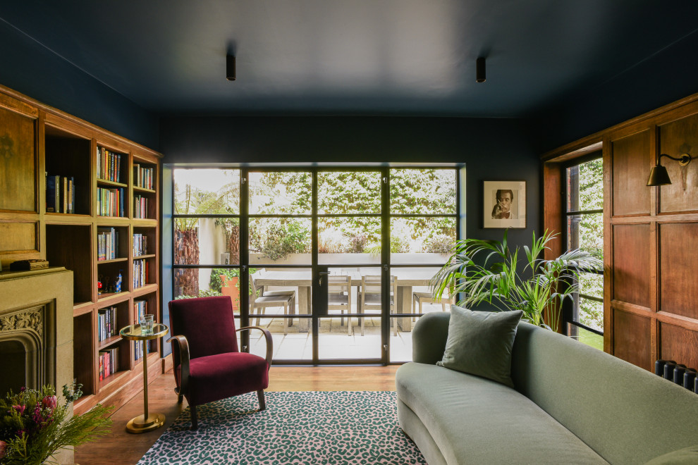 Ispirazione per un soggiorno stile americano di medie dimensioni con pareti blu, parquet scuro, cornice del camino in pietra, pavimento marrone e pannellatura