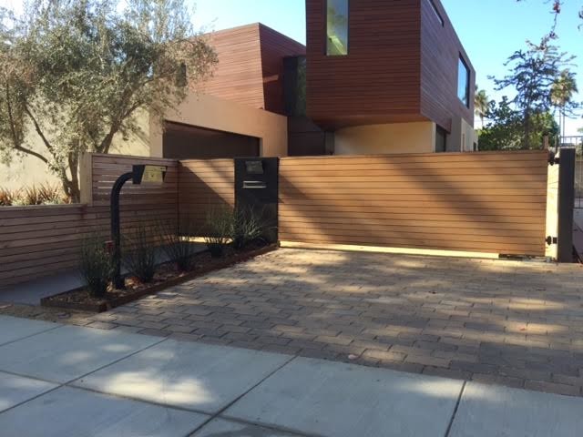 This is an example of a large modern front yard shaded driveway in Los Angeles with brick pavers.