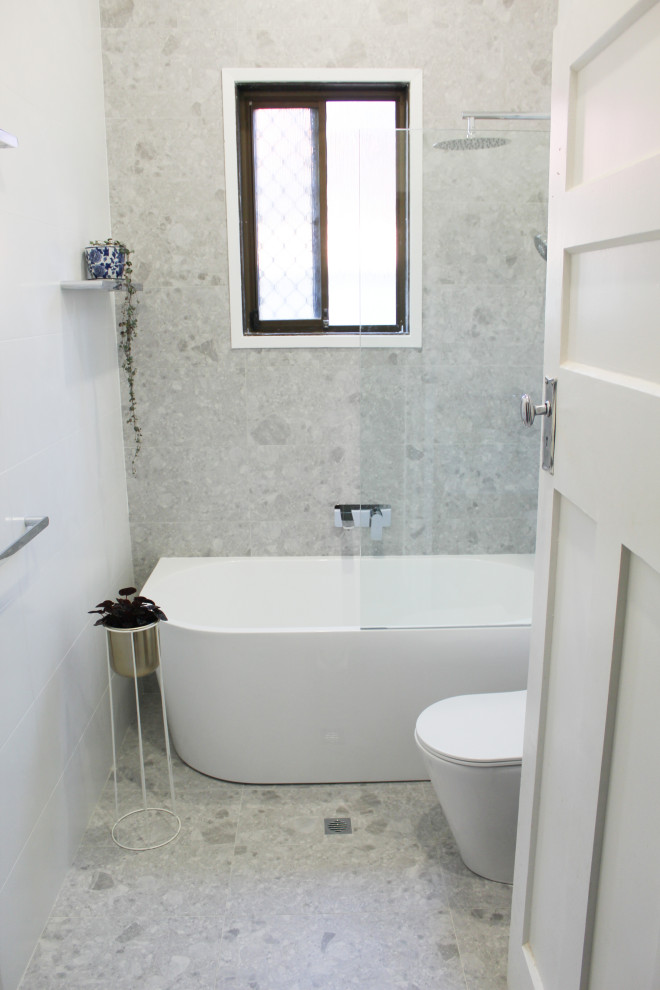 Small modern 3/4 bathroom in Perth with flat-panel cabinets, light wood cabinets, a freestanding tub, a shower/bathtub combo, a one-piece toilet, multi-coloured tile, porcelain tile, white walls, porcelain floors, a vessel sink, marble benchtops, grey floor, white benchtops, a single vanity and a floating vanity.