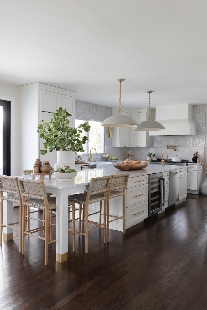 This is an example of a large l-shaped eat-in kitchen in DC Metro with a farmhouse sink, flat-panel cabinets, white cabinets, quartz benchtops, white splashback, engineered quartz splashback, panelled appliances, dark hardwood floors, with island, brown floor and multi-coloured benchtop.