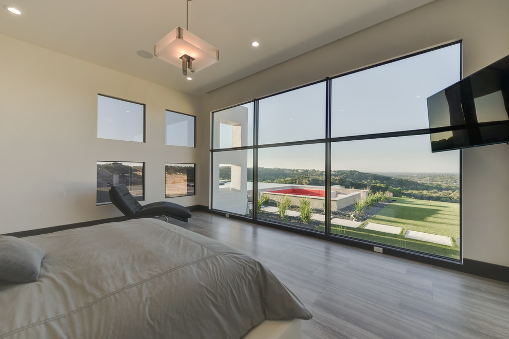 Large modern guest bedroom in Austin with white walls, porcelain floors and brown floor.