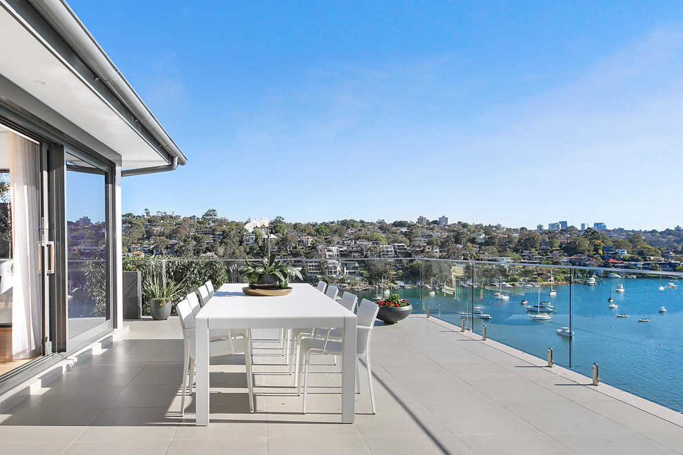 This is an example of a mid-sized contemporary balcony in Sydney with an awning and glass railing.