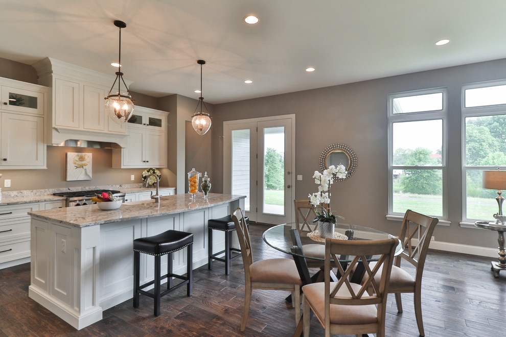 Open concept kitchen - mid-sized transitional l-shaped dark wood floor and brown floor open concept kitchen idea in St Louis with a farmhouse sink, shaker cabinets, white cabinets, granite countertops, gray backsplash, stainless steel appliances and an island