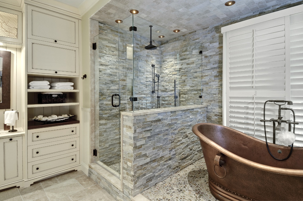 Inspiration for a large transitional master bathroom in Charleston with recessed-panel cabinets, a freestanding tub, a corner shower, stone tile, gray tile, beige walls, porcelain floors, beige floor, a hinged shower door, a vessel sink and beige cabinets.