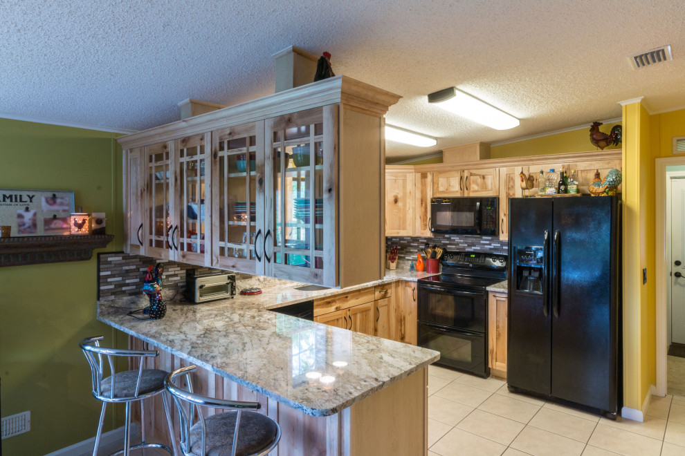 Example of a mid-sized u-shaped cement tile floor and beige floor eat-in kitchen design with an undermount sink, shaker cabinets, light wood cabinets, granite countertops, glass tile backsplash, black appliances, a peninsula and beige countertops