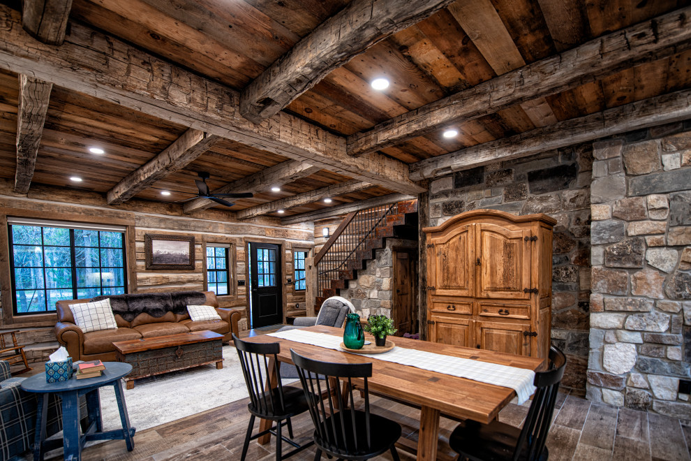 Réalisation d'une salle à manger chalet en bois de taille moyenne avec un mur marron, un sol en bois brun, une cheminée standard, un manteau de cheminée en pierre, un sol marron et un plafond en bois.